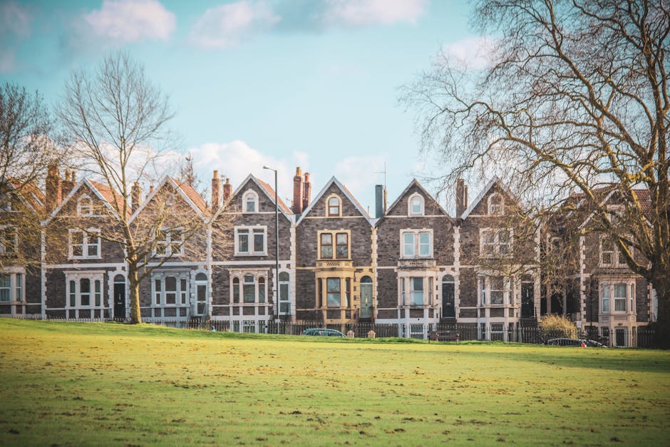 The exterior of a Victorian-style house in Shirley with white weatherboarding and large bay windows, part of a home undergoing furniture transport and packing for a house removal. In the foreground, green shrubs and plants are visible along the base of the building. Exterior walls include brickwork at the lower level and decorative woodwork and detailed cornices around the bay windows. The clear blue sky provides natural light, illuminating the façade. This setting suggests active packing or preparation for a home relocation, with the focus on safeguarding the property during furniture loading processes. Man with Van Shirley, a professional removals service, routinely arranges careful loading of furniture and boxes to prevent damage, especially when dealing with historic Victorian houses like this one.